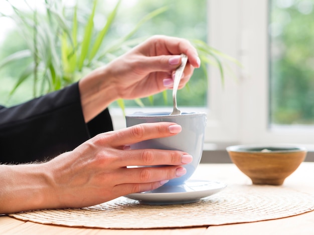 Frau, die Teelöffel von Teetasse nimmt