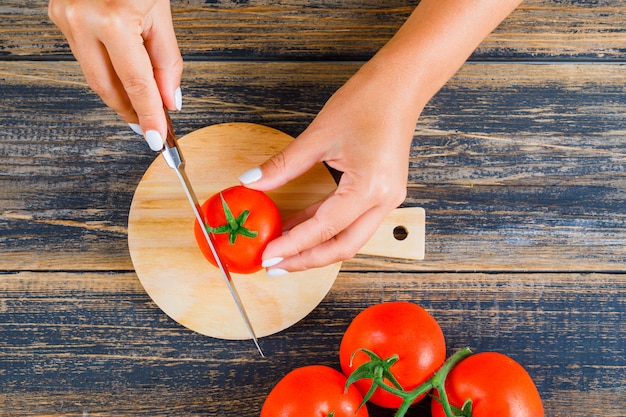 Frau, die Tomate mit Messer schneidet