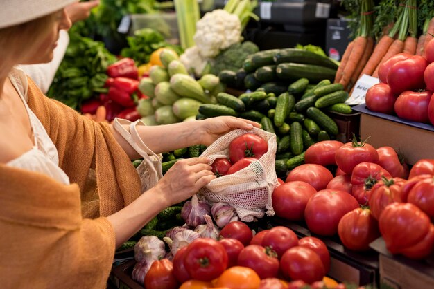 Frau, die Tomaten vom Marktplatz kauft