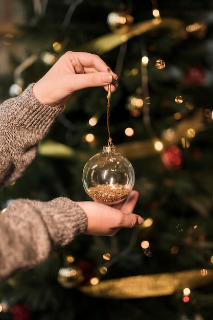 Frau, die transparenten Weihnachtsball der Verzierung hält