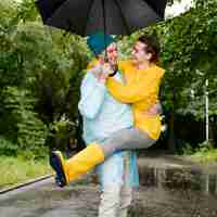 Kostenloses Foto frau, die über ihren ehemann unter dem regenschirm springt