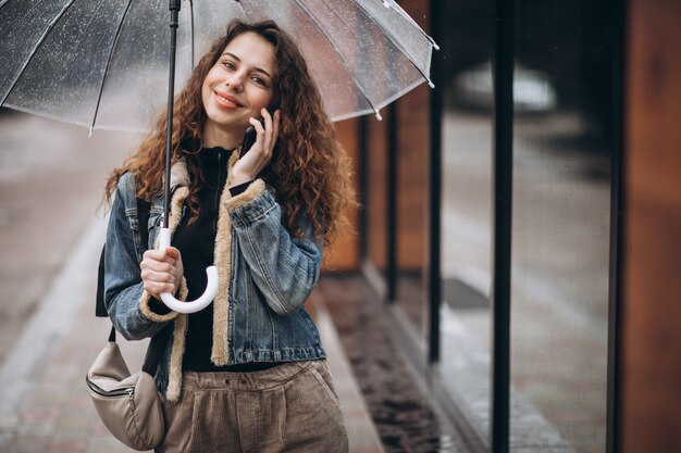 Frau, die unter dem Regenschirm in einem regnerischen Wetter geht