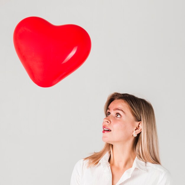 Frau, die Valentinsgrußballon betrachtet