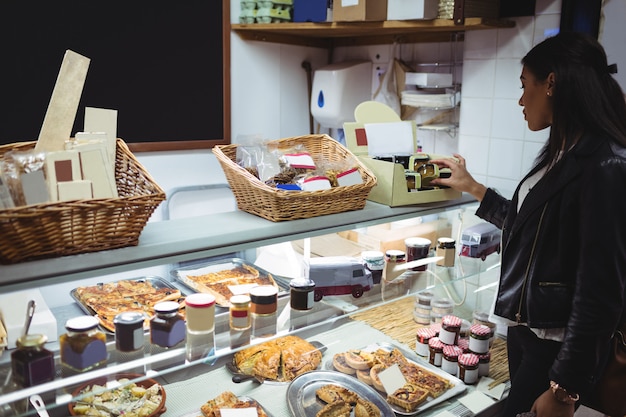 Frau, die verpacktes Essen am Lebensmittelschalter auswählt