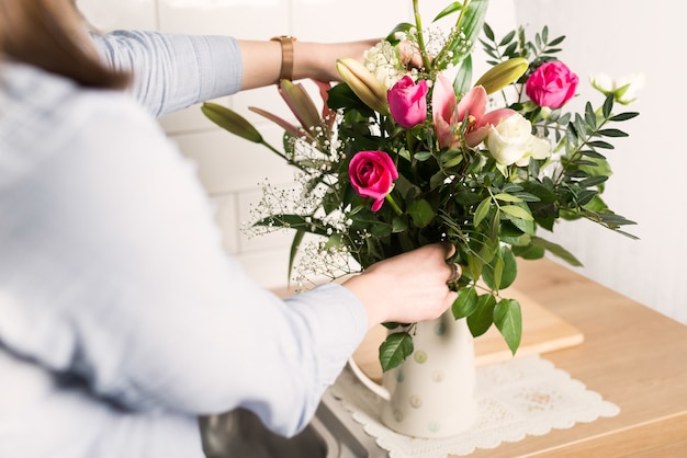 Frau, die verschiedene Blumen in einer Vase anordnet