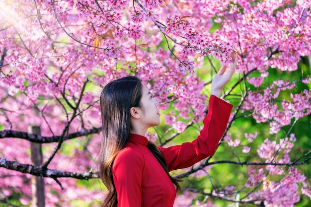 Kostenloses Foto frau, die vietnamkultur traditionell im kirschblütenpark trägt.