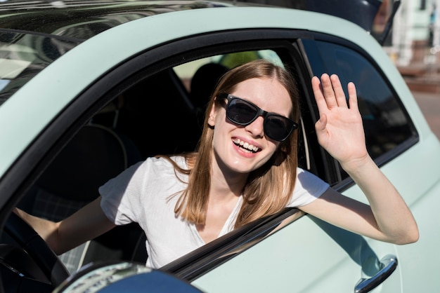 Frau, die vom Auto vor der Reise winkt