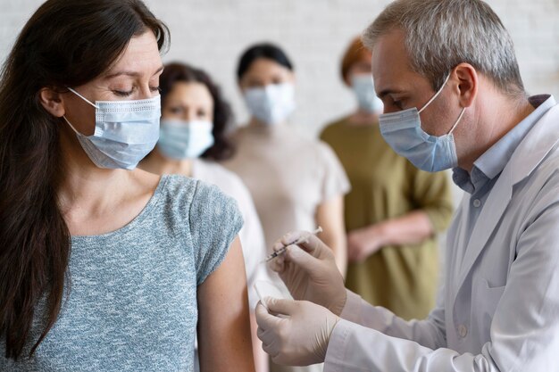 Frau, die von Arzt mit medizinischer Maske impfen lässt