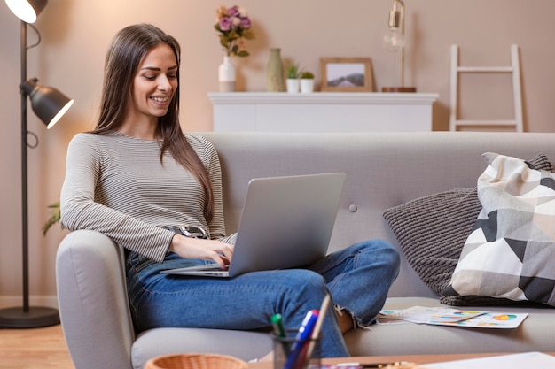 Frau, die von einer bequemen Couch arbeitet