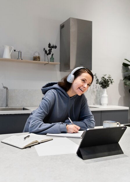 Frau, die von zu Hause aus in der Küche mit Tablet arbeitet