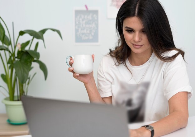 Frau, die von zu Hause mit Tasse Kaffee arbeitet