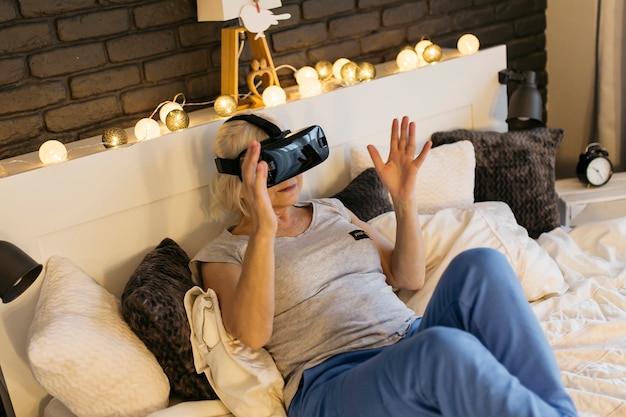 Frau, die VR-Gläser auf Bett verwendet