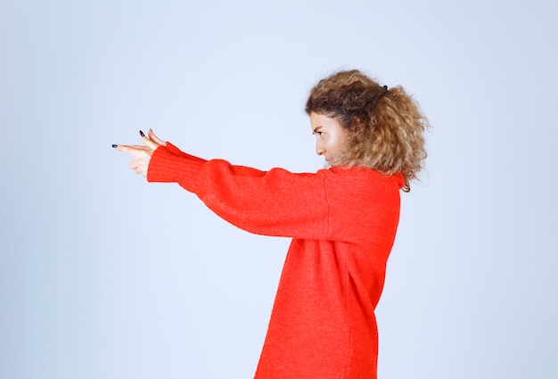 Kostenloses Foto frau, die waffenzeichen in der hand zeigt.