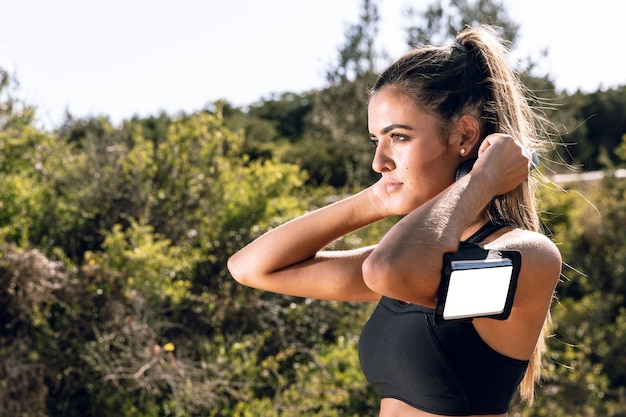 Kostenloses Foto frau, die weg mit telefonarmbandmodell schaut