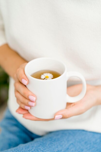 Frau, die weißen Becher mit Tee hält