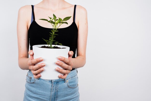 Frau, die weißen Blumentopf mit Kopienraum hält