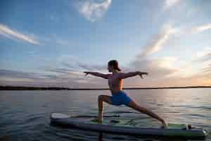 Kostenloses Foto frau, die yoga auf paddleboard-seitenansicht macht