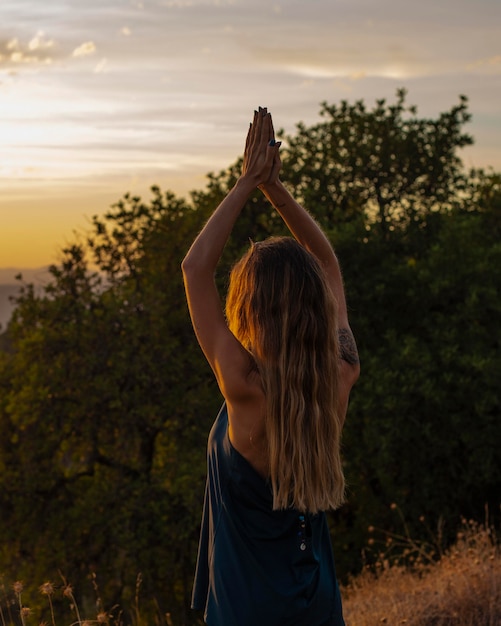 Frau, die Yoga macht, während sie den Sonnenuntergang beobachtet