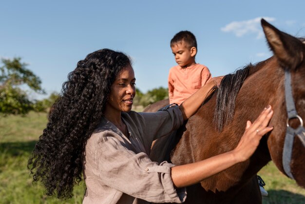Frau, die Zeit mit ihrem Pferd und ihrem Sohn verbringt