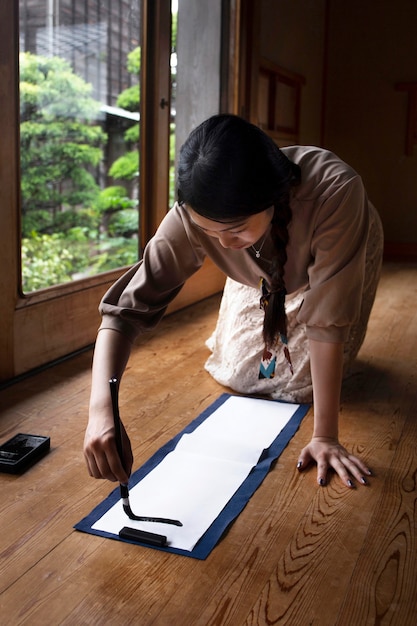 Kostenloses Foto frau, die zu hause japanische handschrift übt