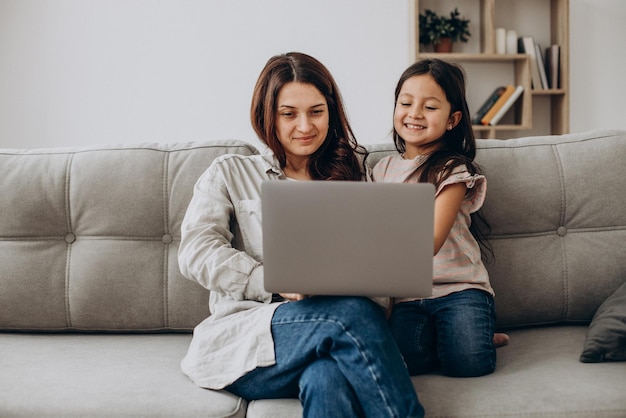 Frau, die zu Hause mit Tochter online am Laptop arbeitet