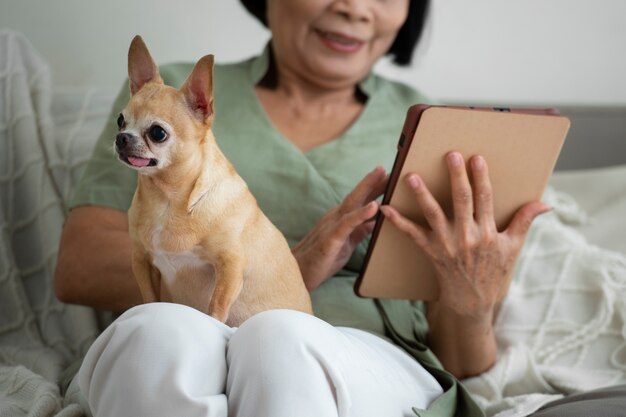 Frau, die zu Hause neben ihrem Hund ein Tablet verwendet