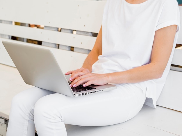 Frau draußen auf Bank, die am Laptop arbeitet