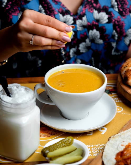 Frau drücke Zitrone in Linsensuppe