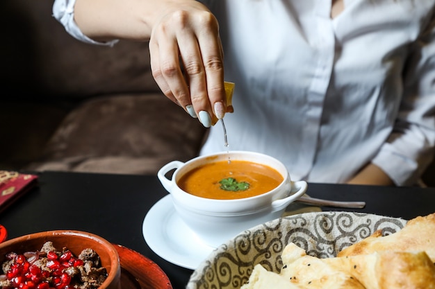 Frau drücken Zitrone in Linsensuppe Seitenansicht