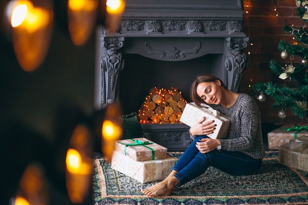 Frau durch den Weihnachtsbaum, der Geschenke auspackt