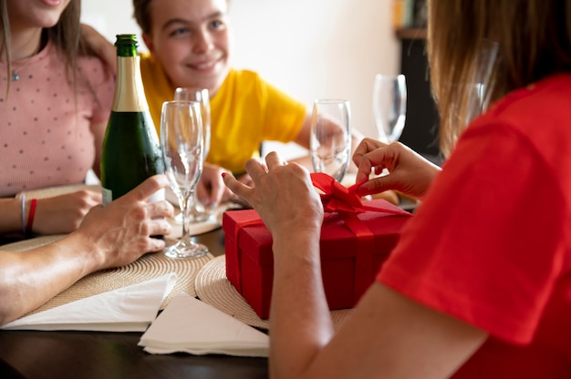 Frau erhält Geschenk beim Abendessen umgeben von Familie