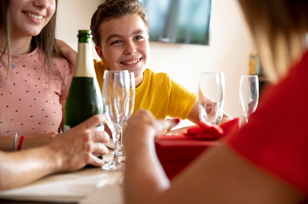 Frau erhält Geschenk beim Abendessen umgeben von Familie