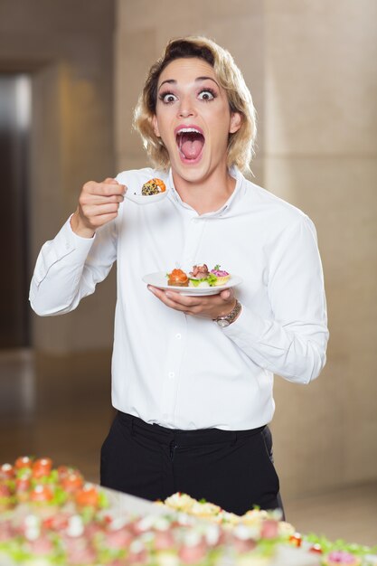 Frau Essen Snacks mit weit geöffnetem Mund und Augen