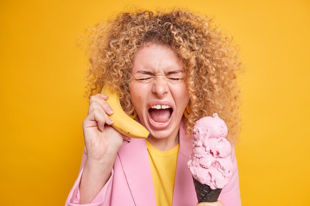 Kostenloses Foto frau excalims hält laut die hand in der nähe des ohrs, als ob das telefon vorgibt, jemanden anzurufen, der eis in der waffel hält, was sehr emotional ist