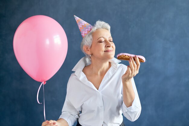 Frau feiern Geburtstag mit Ballon, der Gebäck isst