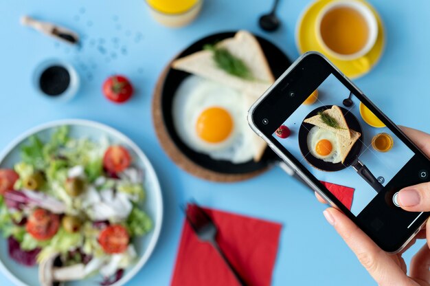 Frau fotografiert Ei mit Toast