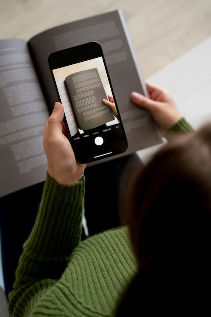 Frau fotografiert eine Zeitschrift mit ihrem Smartphone