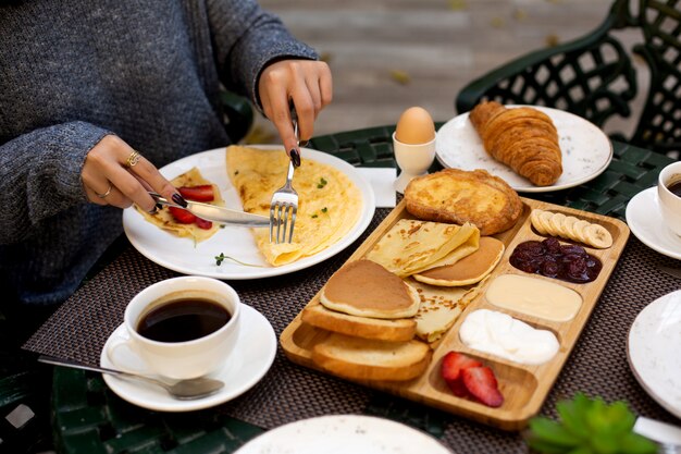 Frau frühstückt mit Omelett und Crêpe