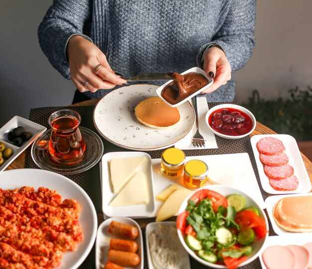 Frau frühstückt mit Pfannkuchen und Schokoladencreme