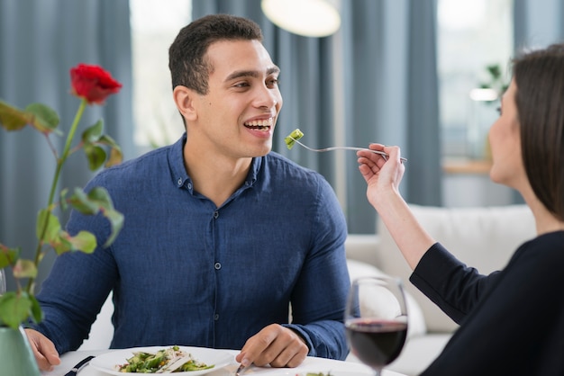 Frau füttert ihren Mann bei einem romantischen Abendessen
