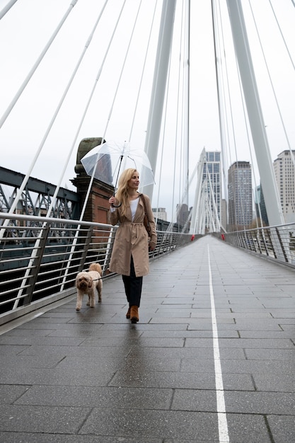 Frau geht bei Regen mit ihrem Hund auf einer Brücke spazieren