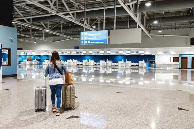 Frau geht mit Koffern am Flughafen entlang