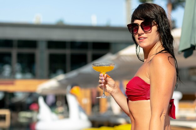 Frau genießt ihren Tag am Pool mit Cocktail