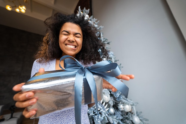 Frau gibt seinem Freund in der Kamera ein Geschenk Porträt einer jungen Frau mit Afro-Aussehen, ethnischer schwarzer Brünette mit lockigem Haar