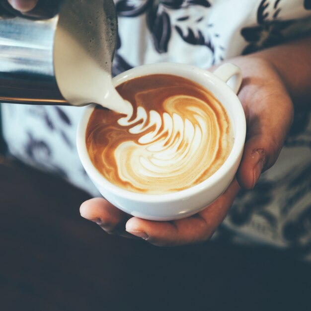 Frau gießt Kaffeesahne