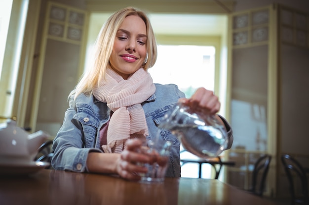 Frau gießt Wasser aus Krug in Glas