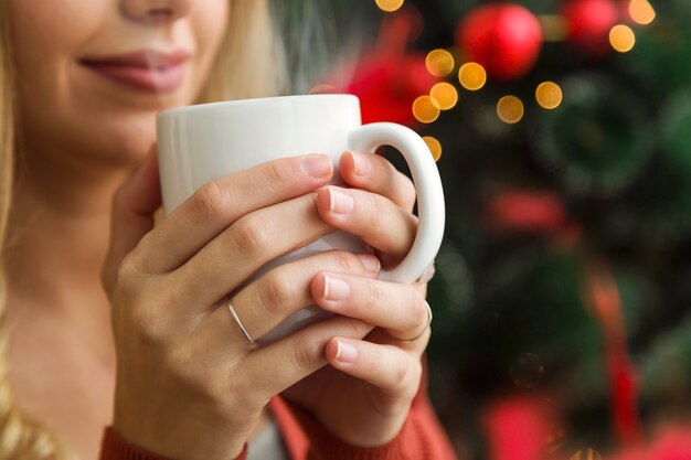 Frau hält eine Tasse vor ihr Gesicht