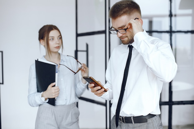 Frau hält einen Ordner. Geschäftspartner bei einem Geschäftstreffen. Mann benutzt das Telefon. Menschen mit Brille