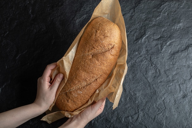 Frau hält eingewickeltes frisches Brot.