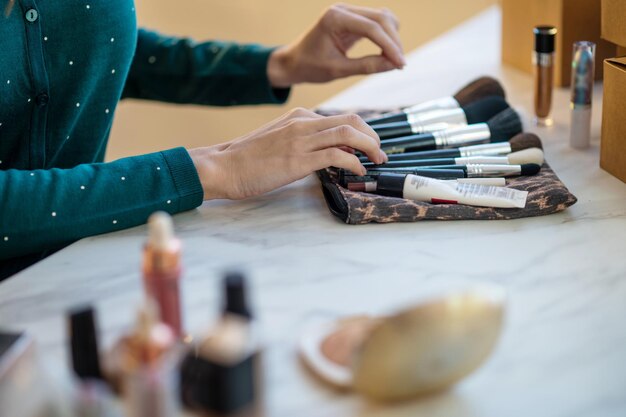 Frau hält Gesichtsbürste und macht Make-up